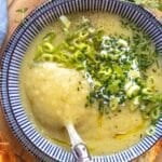Bowl of healthy creamy potato soup served with bread and fresh herbs.