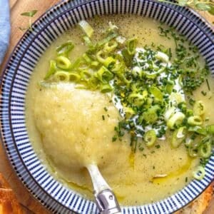 Bowl of healthy creamy potato soup served with bread and fresh herbs.