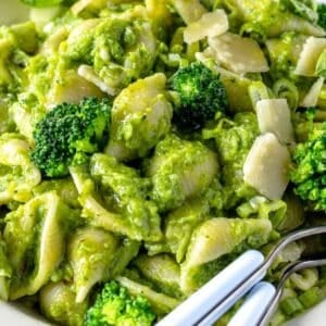 Bowl of smashed broccoli pasta with parmesan cheese and basil ready to serve.