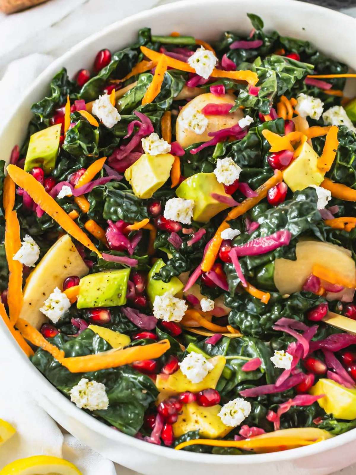 Close up Mediterranean kale salad with feta apple avocado and pomegranate seeds