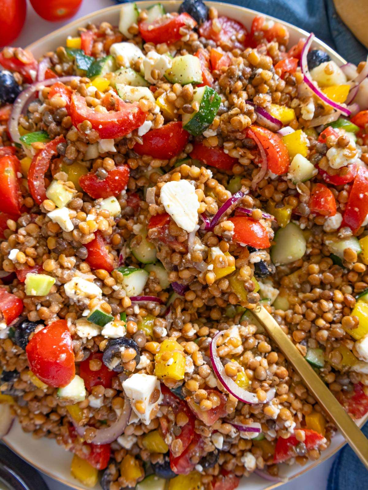 Close up finished Greek lentil salad with feta olives and fresh vegetables.