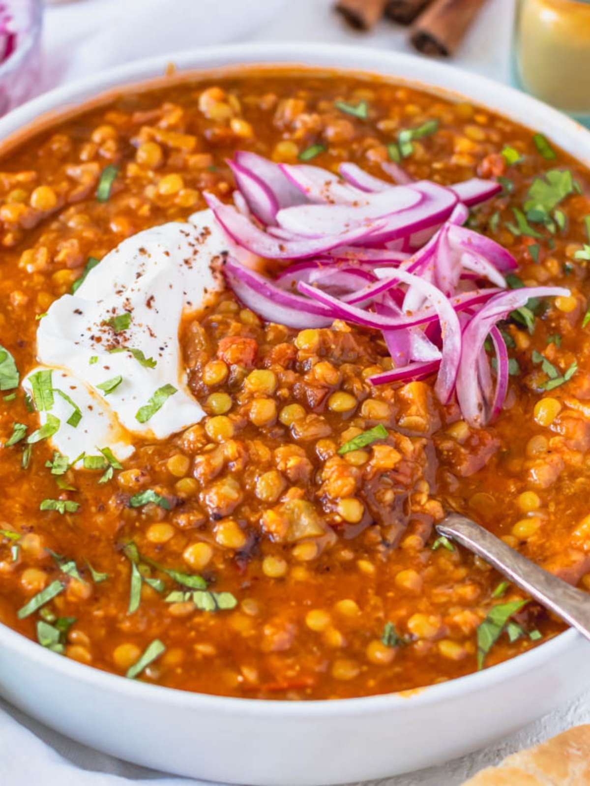 Close up of spiced lentil soup with lemon yogurt and parsley garnish.