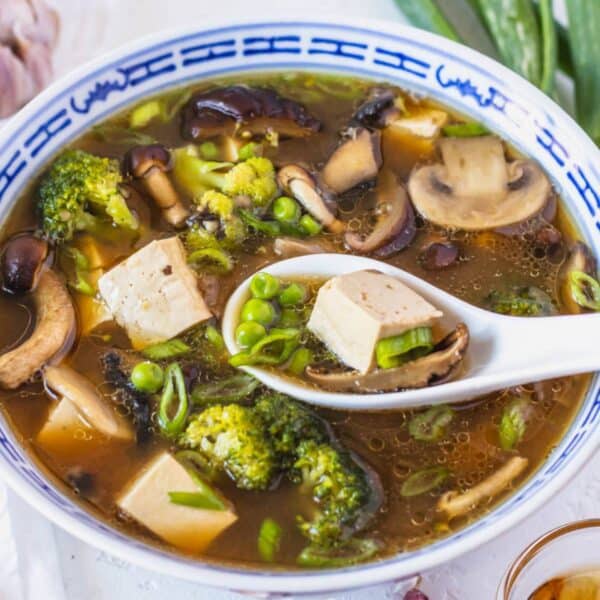 Comforting tofu mushroom soup served hot with tofu shiitake mushrooms and green vegetables.