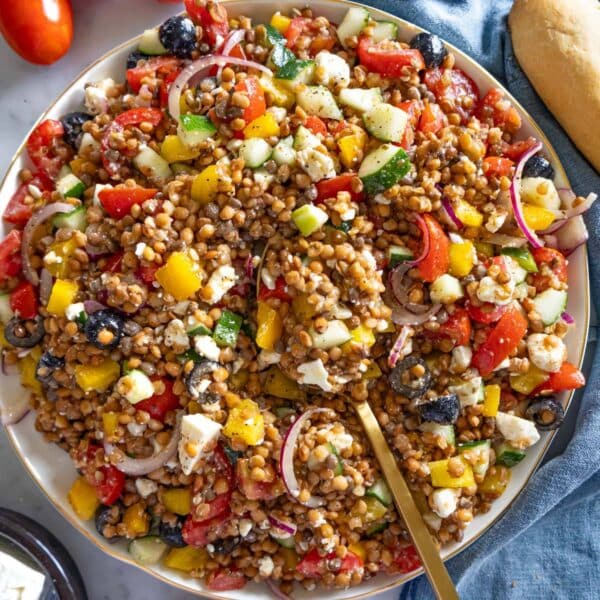 Fresh Greek lentil salad with feta cucumber tomatoes and olives served on a platter.