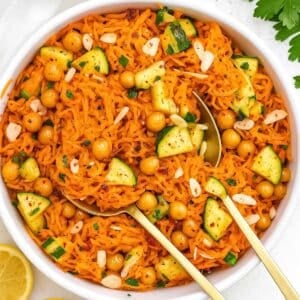 Fresh carrot chickpea salad with cucumber parsley and almonds served in large bowl.