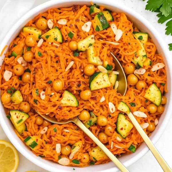 Fresh carrot chickpea salad with cucumber parsley and almonds served in large bowl.