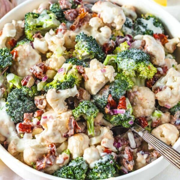 Fresh healthy broccoli cauliflower salad with Greek yogurt dressing served in a bowl with silver spoon.