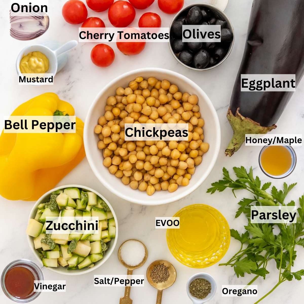 Fresh ingredients for chickpea eggplant salad including eggplant chickpeas zucchini tomatoes and olives.