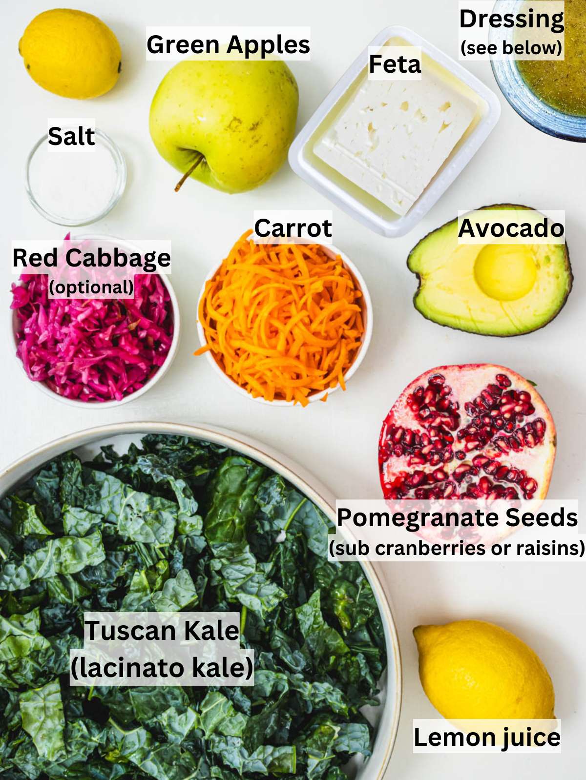 Fresh kale apple avocado carrot feta cheese and pomegranate seeds on kitchen counter.