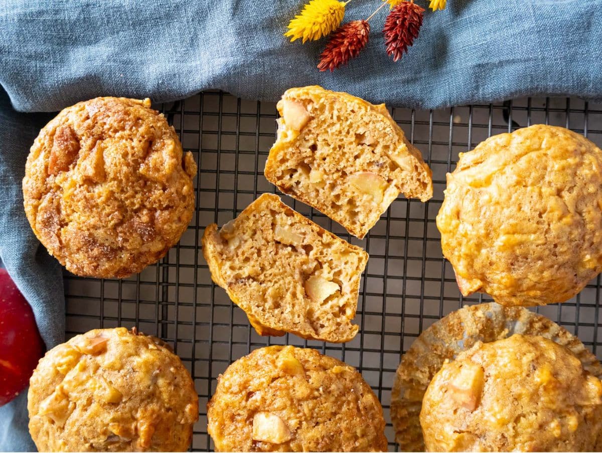 Freshly baked protein breakfast muffins displayed with apples on a cooling rack.