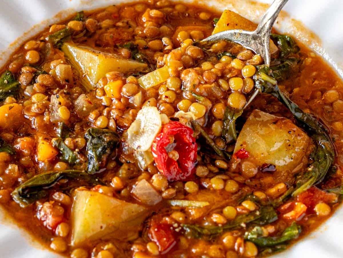 Healthy Mediterranean lentil soup with fiber and protein served in white bowl with olive oil drizzle.