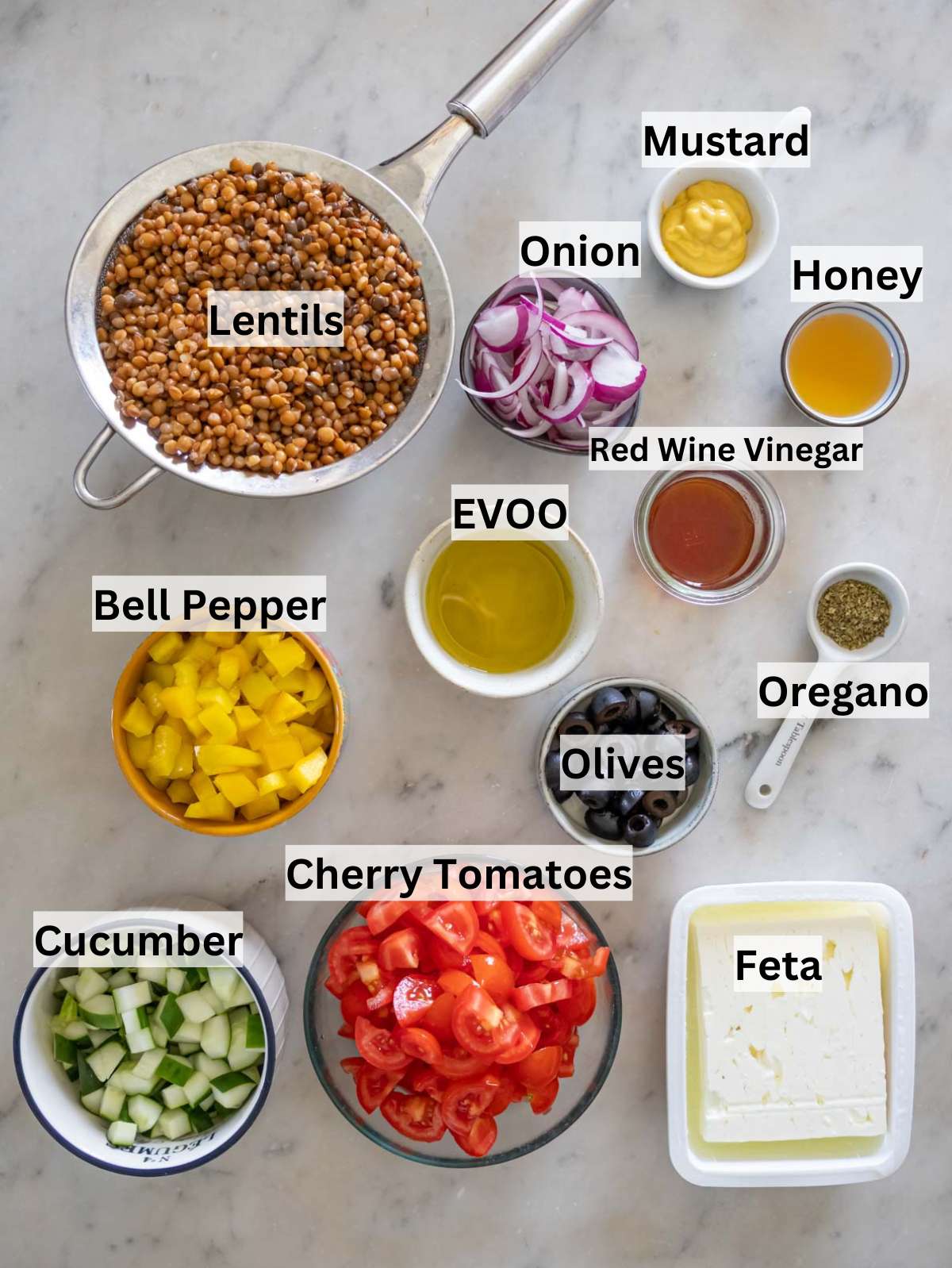 Ingredients for Greek lentil salad arranged on a table with vegetables feta and olives.