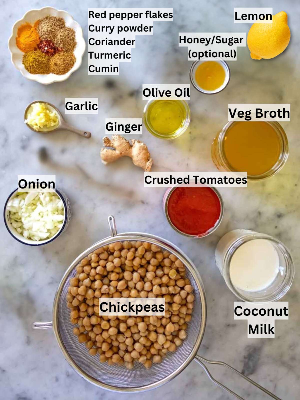 Ingredients for coconut curry with chickpeas including spices onion garlic tomatoes and coconut milk.