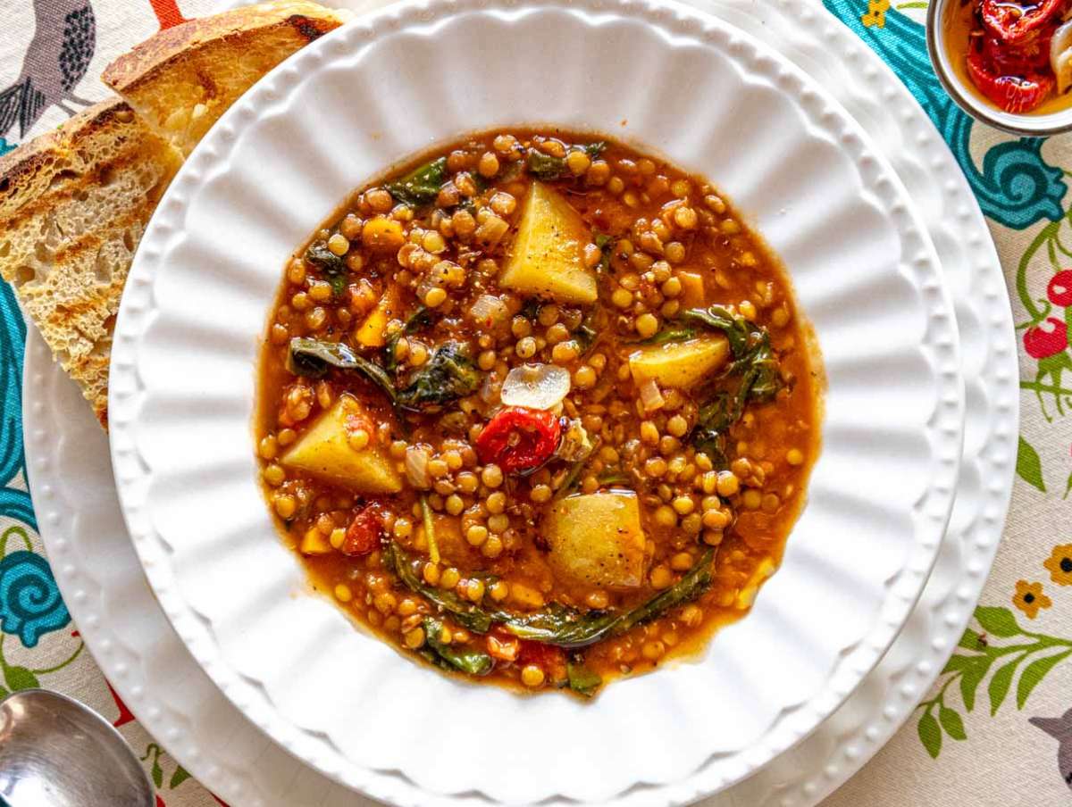 Mediterranean lentil soup served with crusty bread olive oil and optional toppings.