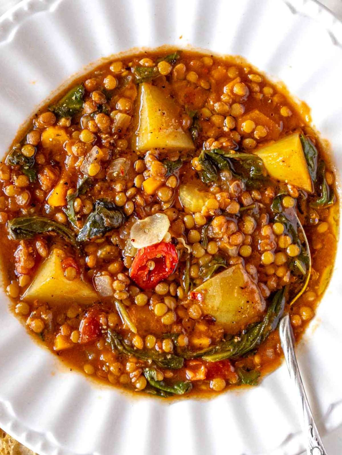 Overhead view of Mediterranean lentil soup with carrots potatoes and leafy greens.