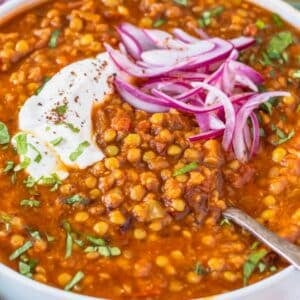 Spiced lentil soup in a bowl with a spoon and yogurt ready to serve for dinner.