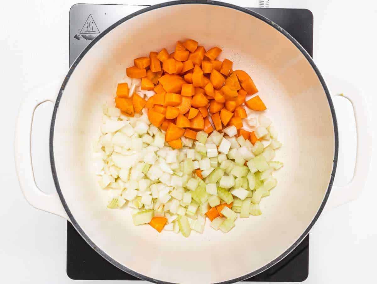 Step 1 Chopped onion carrot celery garlic and herbs cooking in pot for soup flavor base.