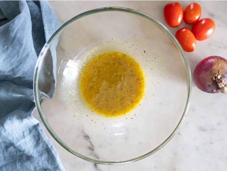 Step 1 Whisking olive oil vinegar mustard honey and oregano to make dressing for Greek lentil salad.