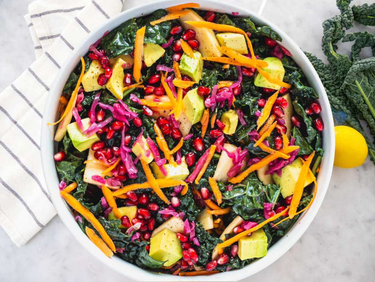 Step 2 Adding apple carrot avocado cabbage and feta to massaged kale salad base.