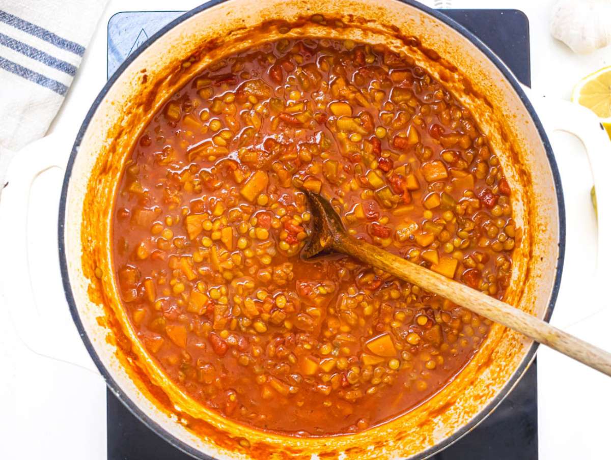 Step 2 Canned lentils crushed tomatoes and broth added to pot simmering into hearty spiced lentil soup.