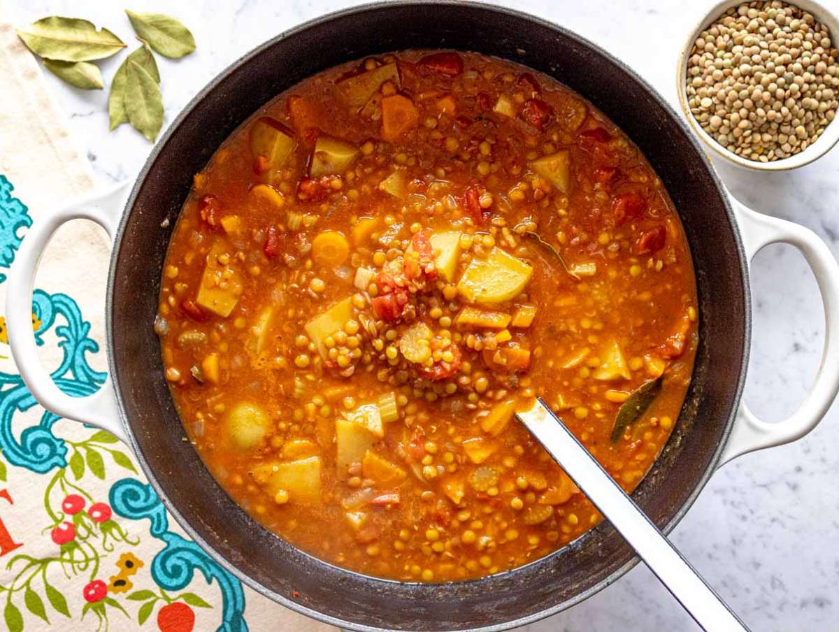 Step 2 Lentils potatoes tomatoes and broth simmering together in large pot for hearty vegetable soup.