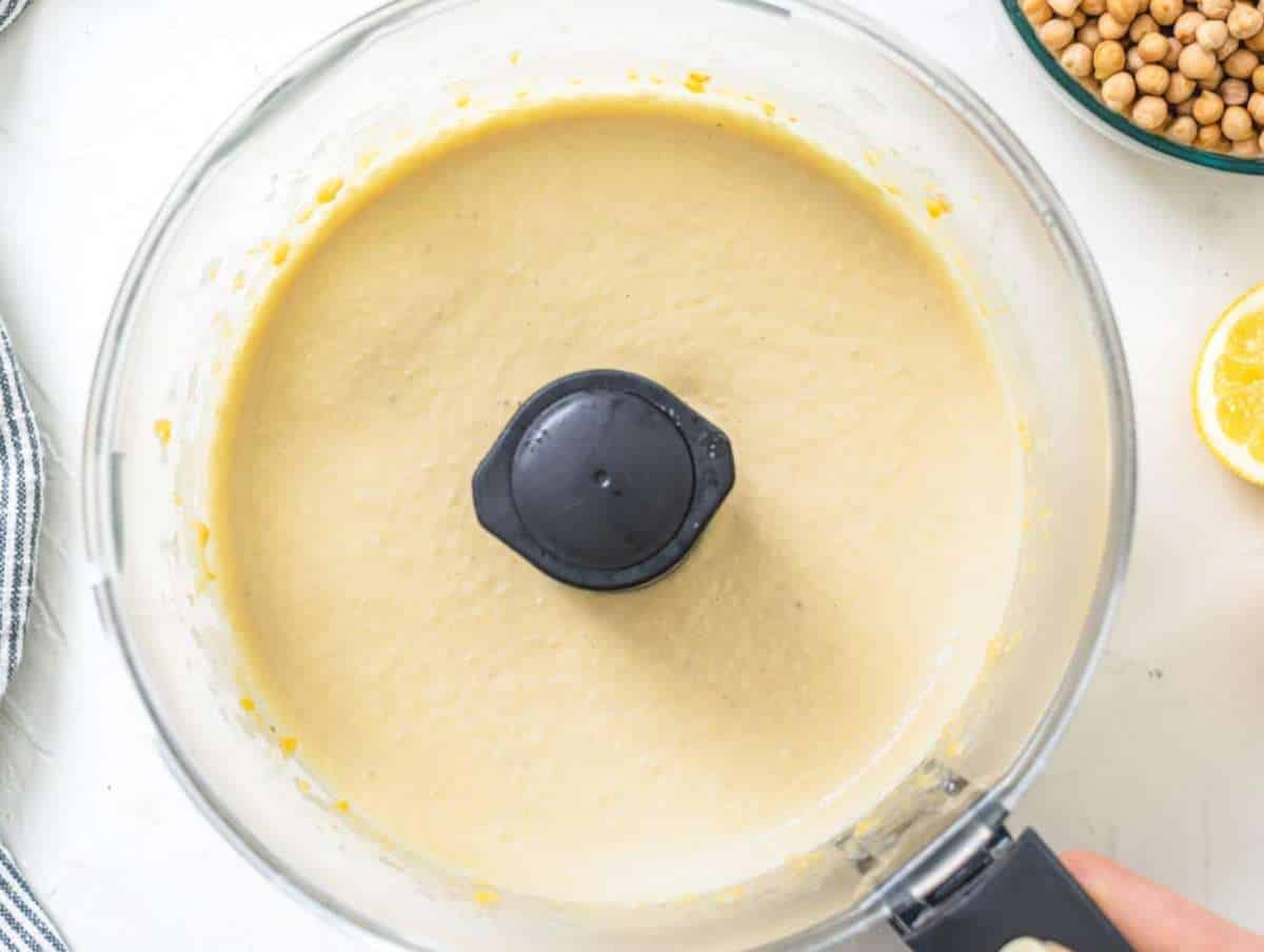 Step 1 Tahini cumin and cold water added to chickpea mix for smooth creamy hummus texture.