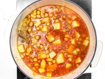 Step 3 Chickpeas potatoes tomatoes and broth simmering together in pot for hearty Mediterranean chickpea soup.