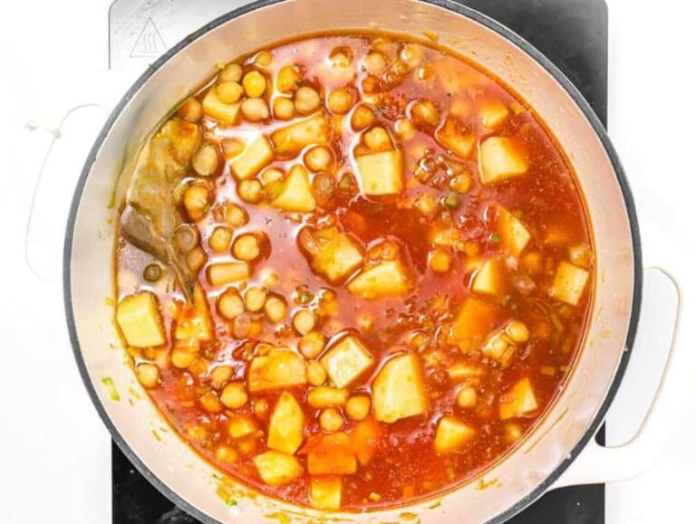 Step 3 Chickpeas potatoes tomatoes and broth simmering together in pot for hearty Mediterranean chickpea soup.