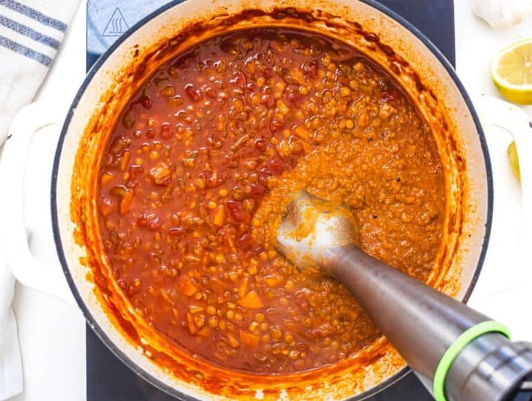 Step 3 Immersion blender pureeing part of spiced lentil soup in pot for creamy rustic texture.