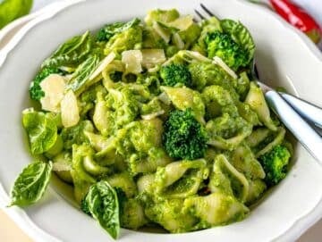 Step 4 Bowl of smashed broccoli pasta topped with basil leaves and shaved parmesan.