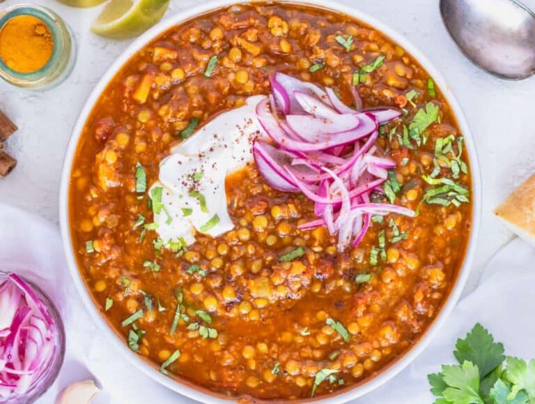 Step 4 Bowl of spiced lentil soup topped with lemon juice parsley and creamy yogurt.