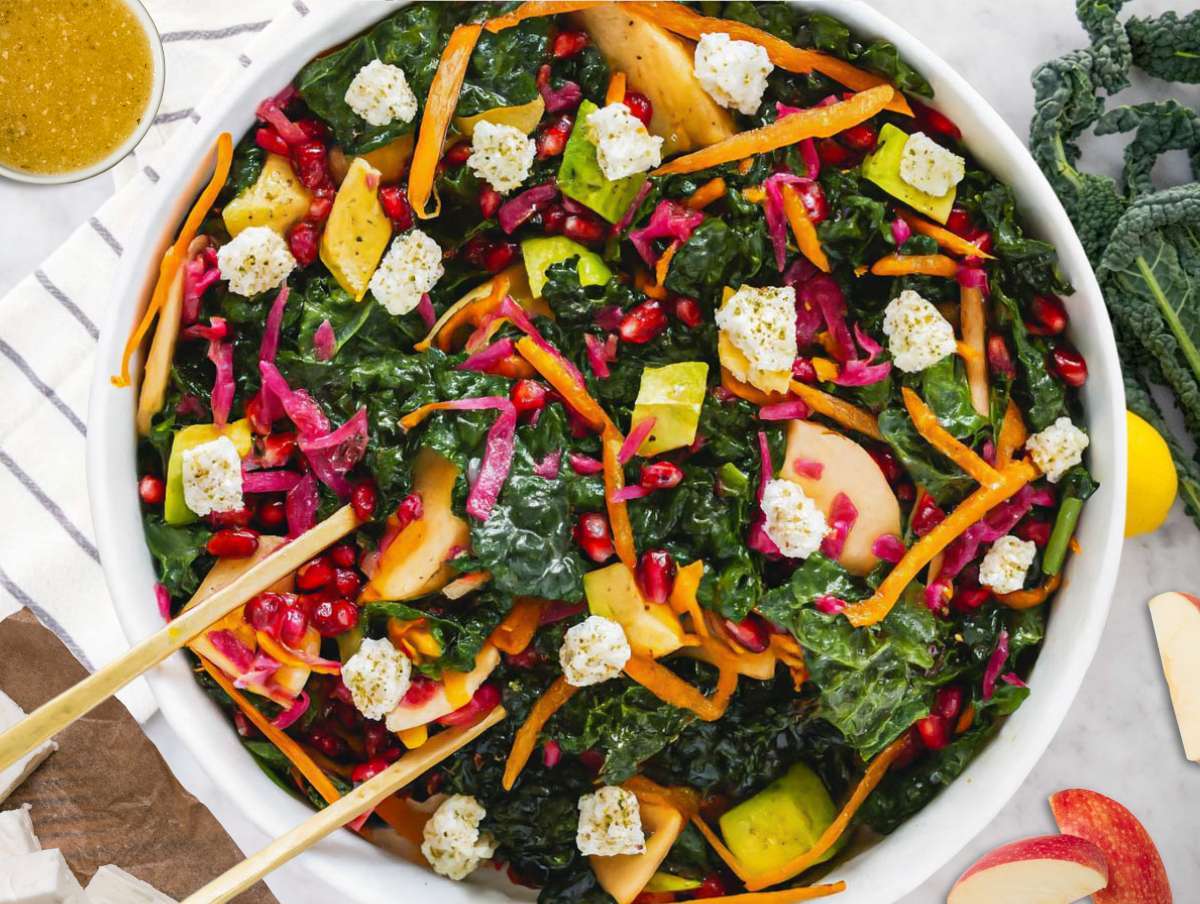 Step 4 Tossing Mediterranean kale salad with feta apple avocado and homemade dressing before serving.