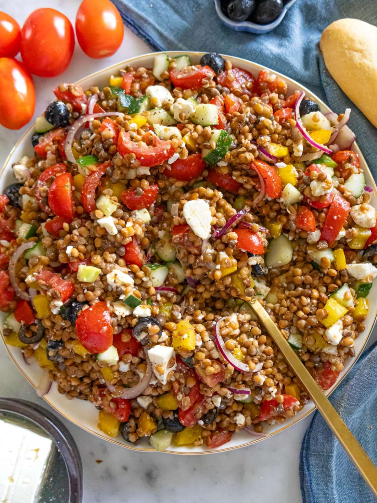 Top down Greek lentil salad on a large platter with colorful vegetables and feta.