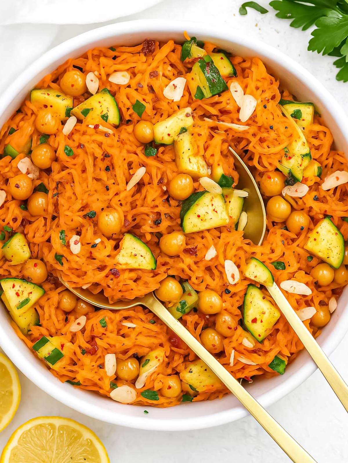 Top down carrot chickpea salad with cucumber almonds and raisins in white bowl.