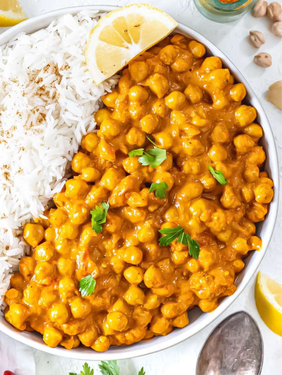 Top down coconut curry with chickpeas in skillet with spinach and basmati rice on side.