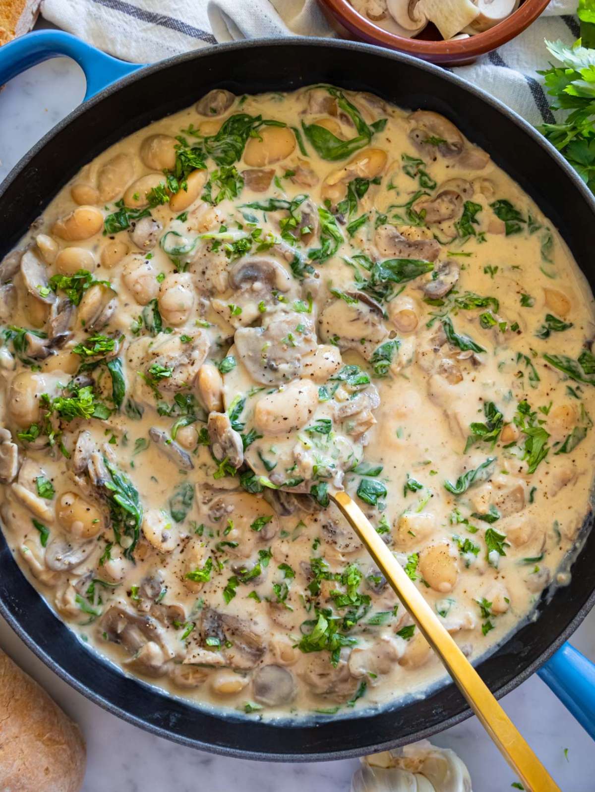 Top down view of Marsala butter beans in creamy sauce with fresh parsley garnish.