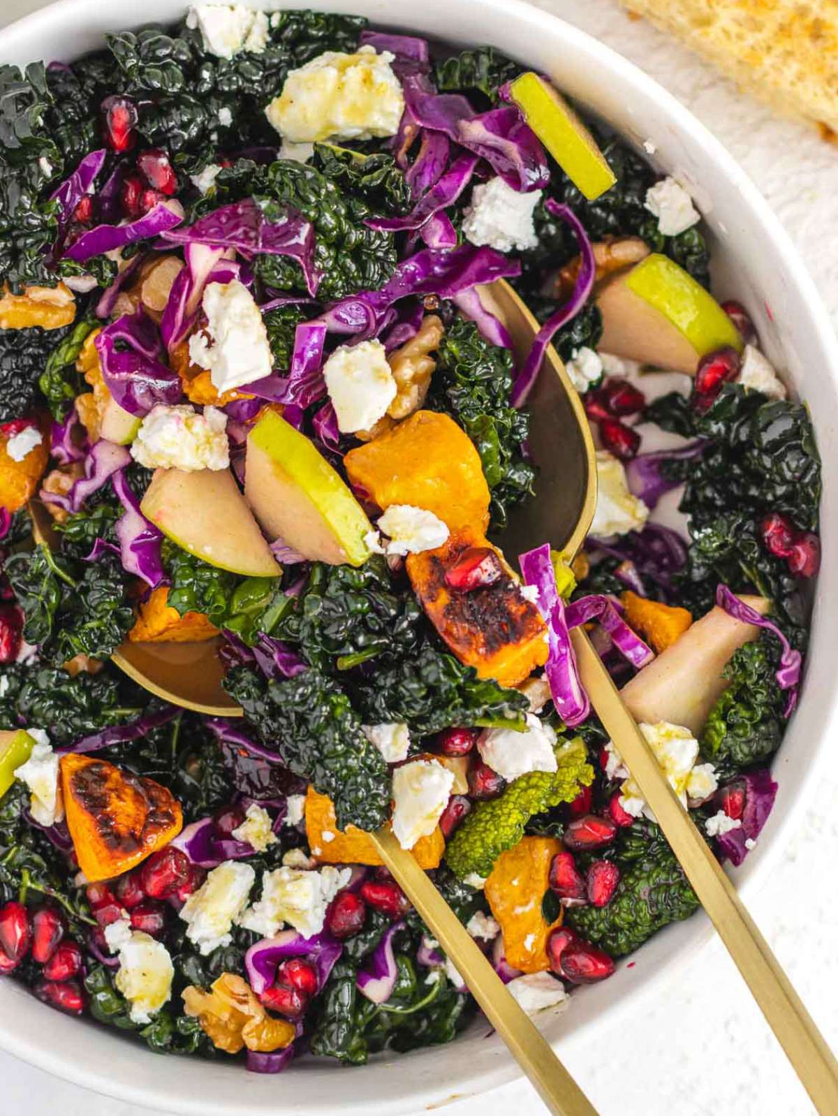 Top down view of colorful butternut squash kale salad with feta walnuts and pomegranate seeds.