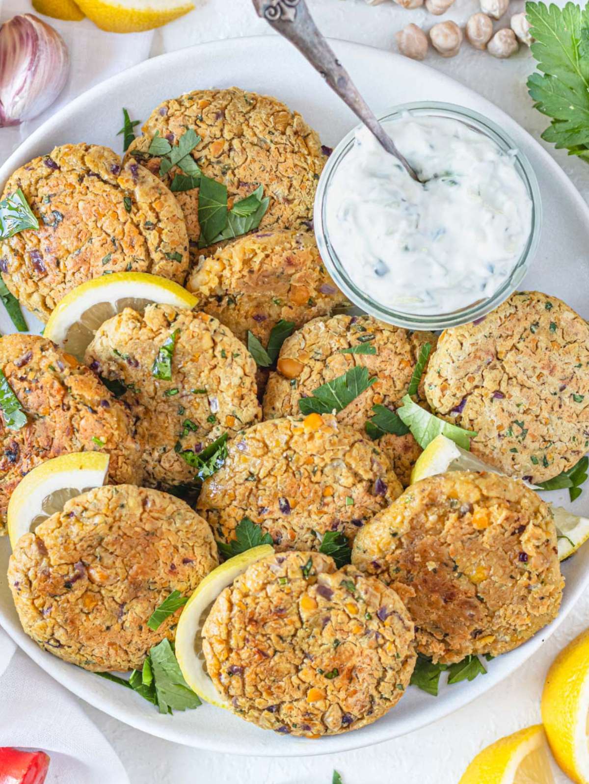 Top down view of golden brown Greek chickpea patties served with lemon wedges.