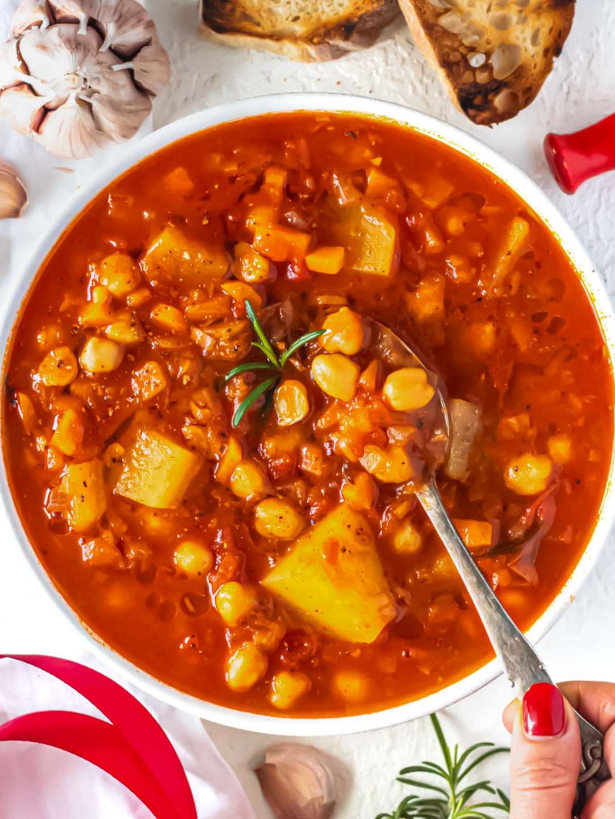Top down view of hearty Mediterranean chickpea soup served with crusty bread on the table.