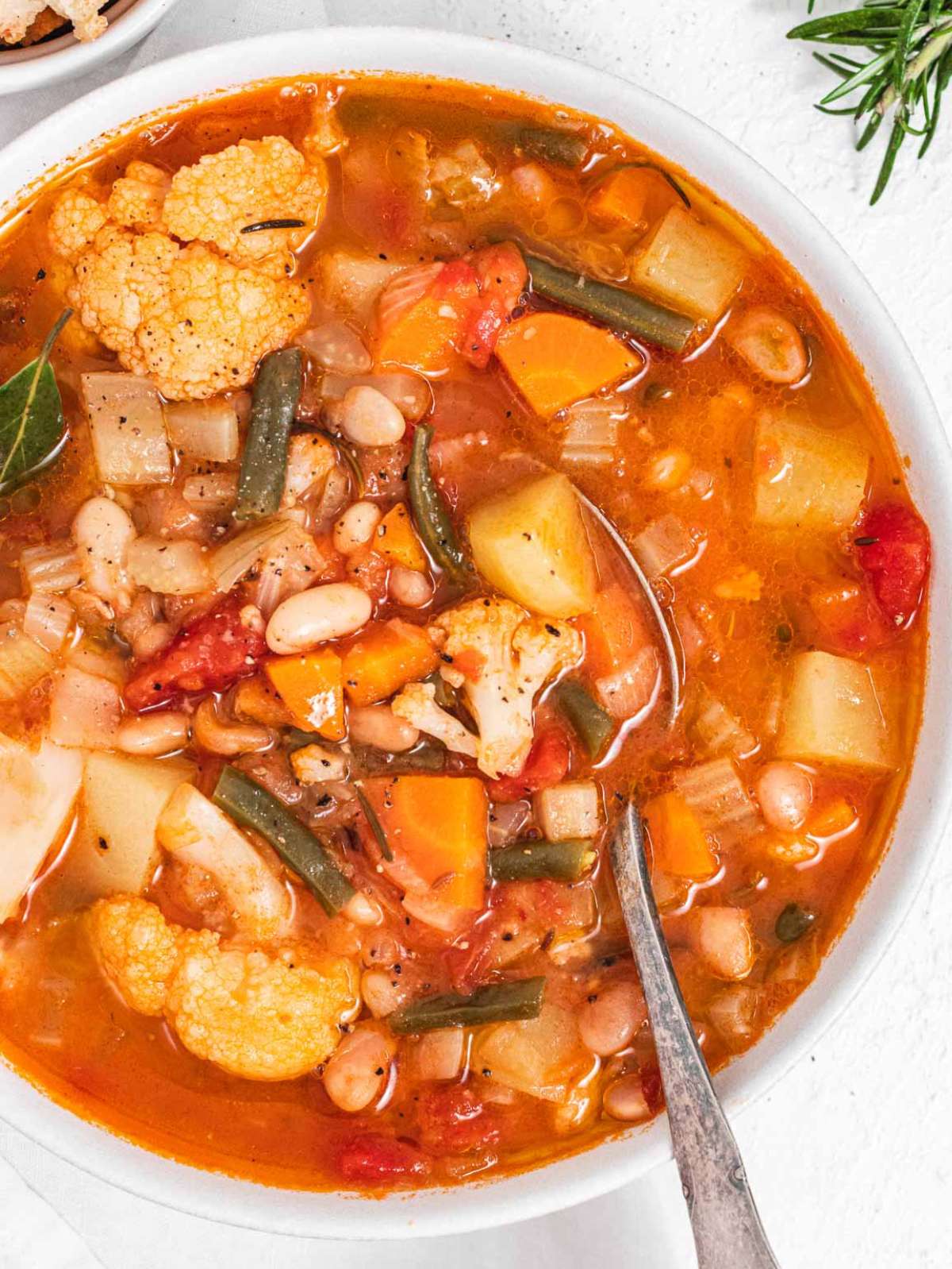 Top down view of hearty Mediterranean vegetable soup with crusty bread on the side.