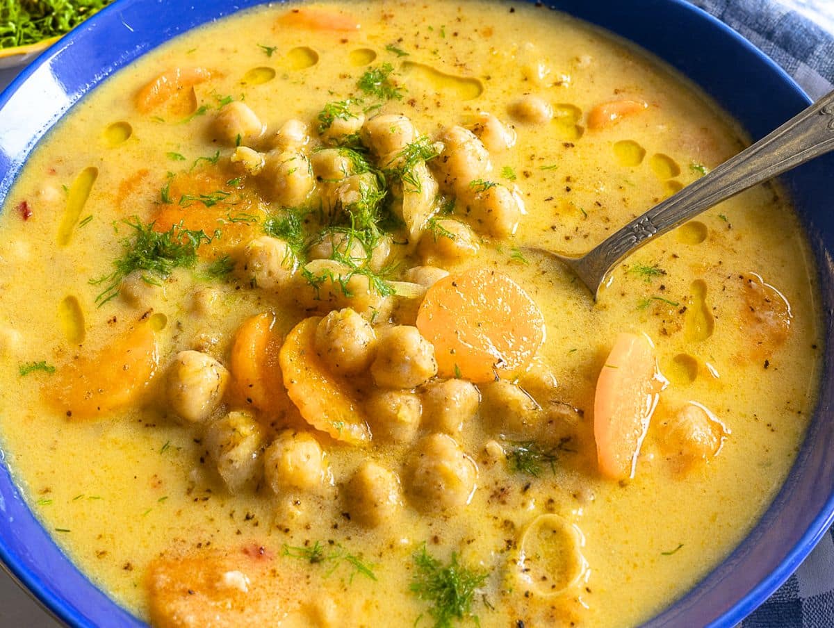 Bowl of Greek chickpea soup Revithia with dill olive oil and a spoon.