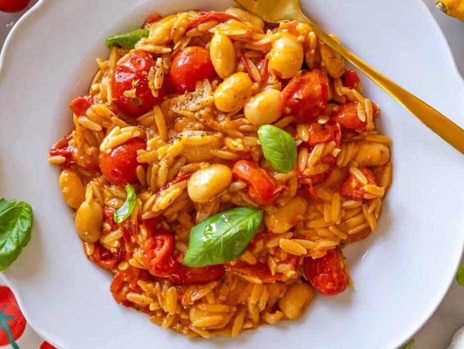 Cherry tomato orzo with butter beans and basil served on a plate.