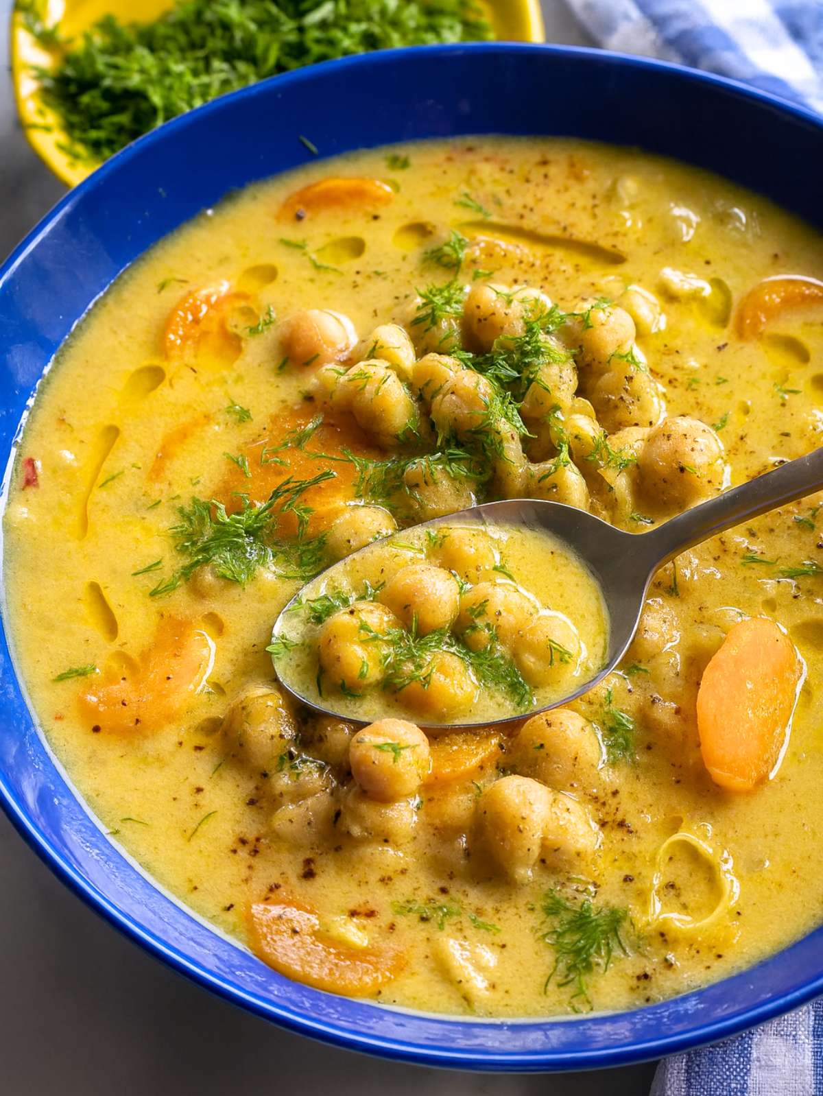 Close-up of Greek chickpea soup with lemon and dill showing creamy texture and olive oil drizzle.