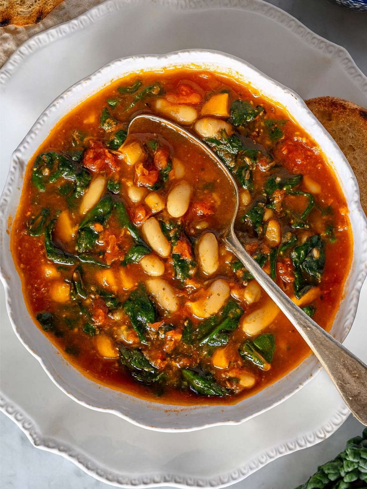 Close-up of Mediterranean kale soup showing tender kale, white beans, and hearty tomato broth.