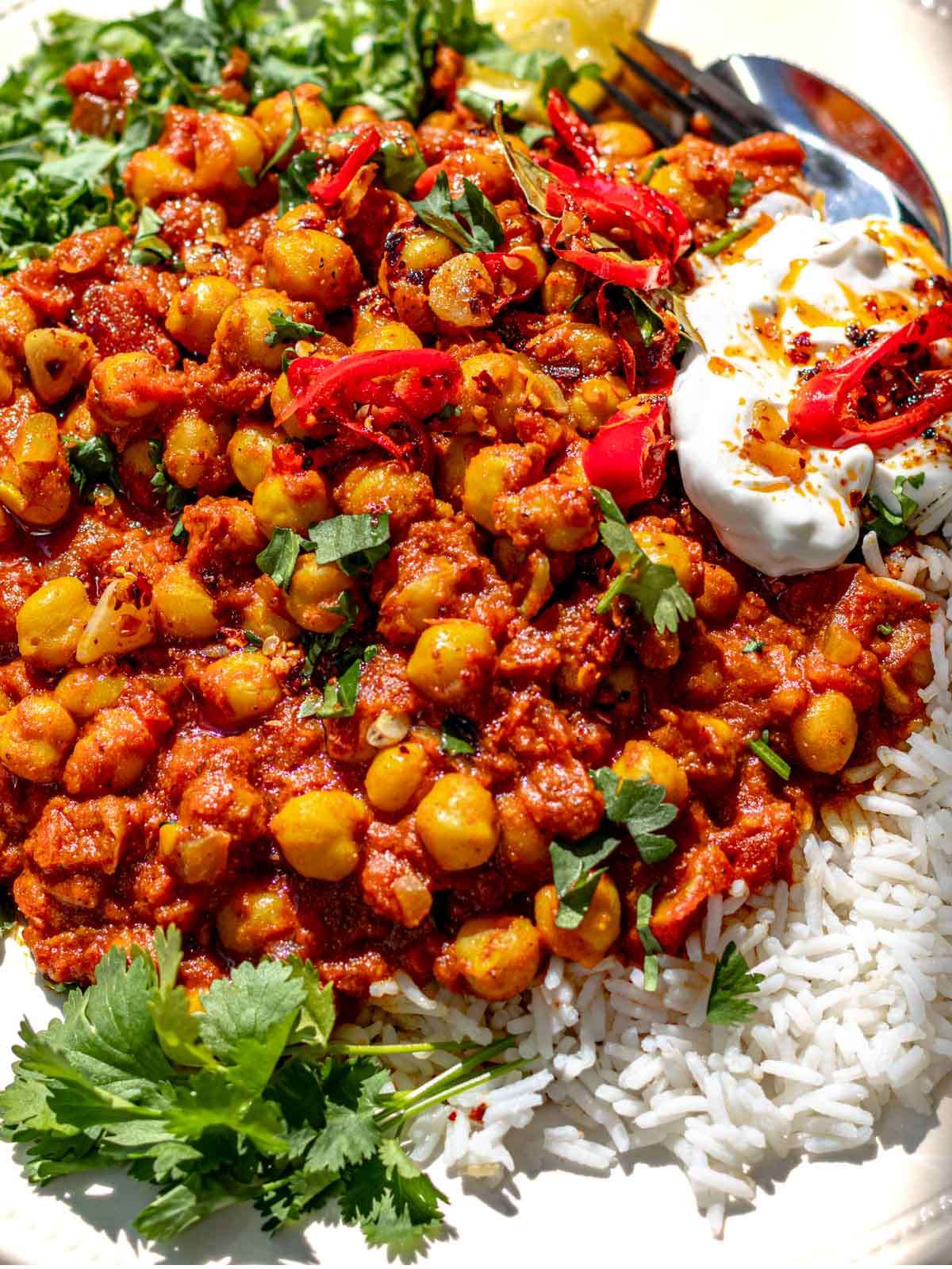 Close up of chickpea masala curry served with rice and fresh cilantro.