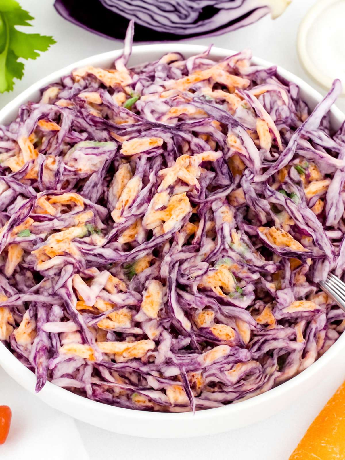 Close up of creamy Greek Yogurt Cabbage Slaw with red cabbage and carrots in a bowl.