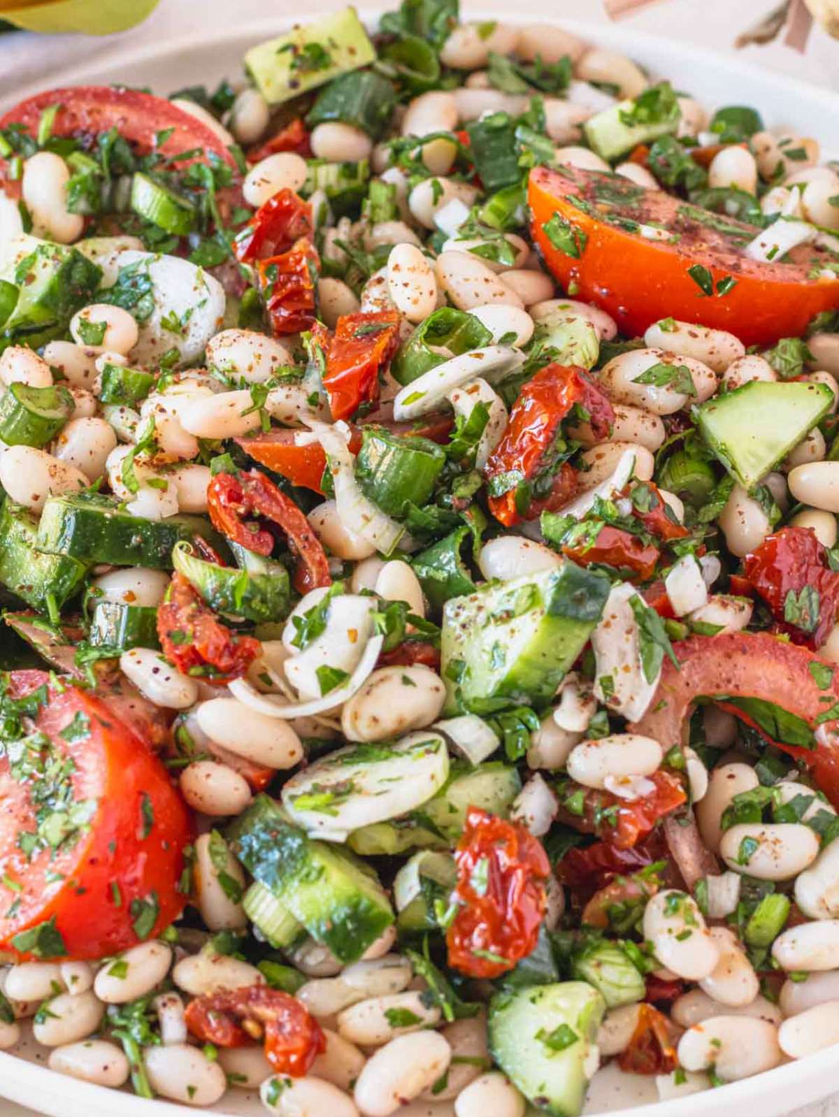 Close up of dense white bean salad with honey mustard dressing and fresh herbs.