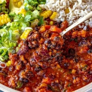 Cozy bowl of chili with beans served with bread and fresh toppings.