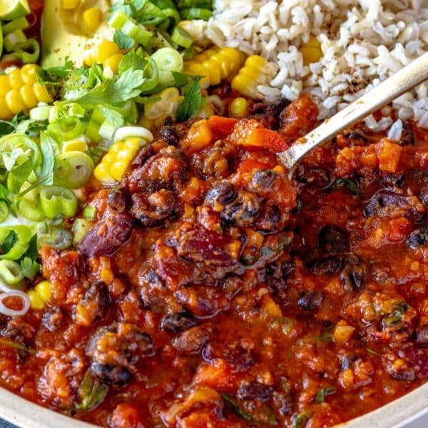 Cozy bowl of chili with beans served with bread and fresh toppings.