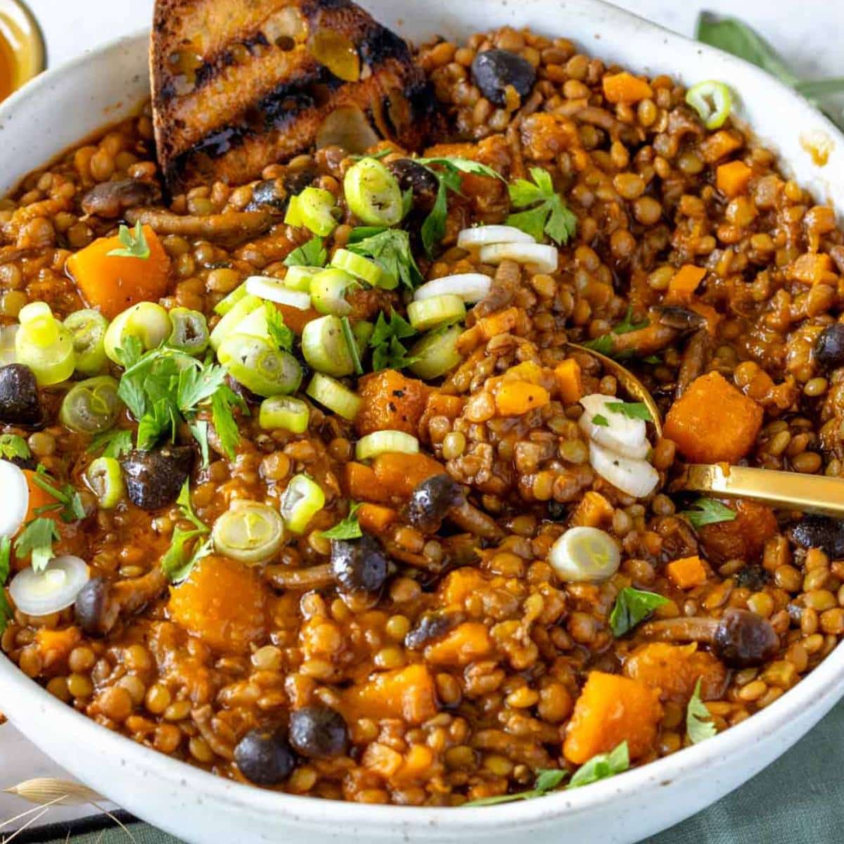 Cozy lentil pumpkin stew with bread on the side for a healthy fall dinner.